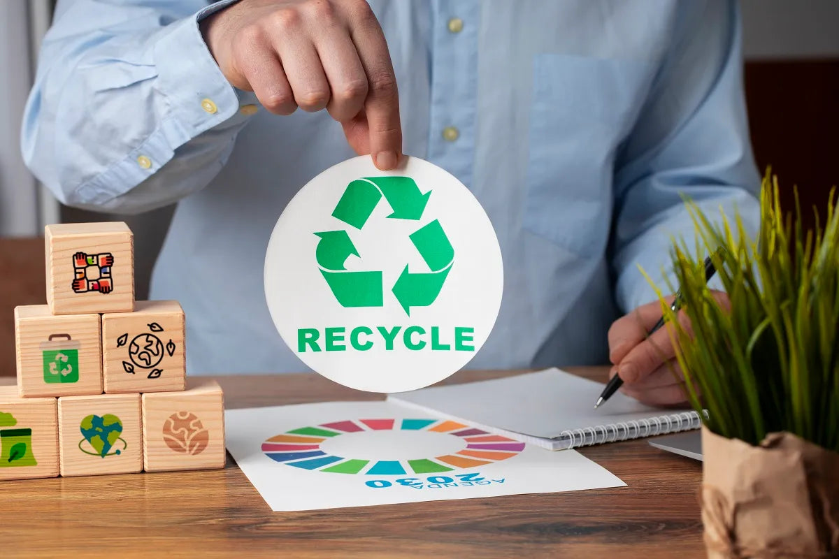 A person holds a paper with Recycle sign