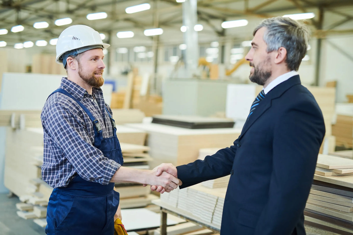 Two men shake hands in plywood factory