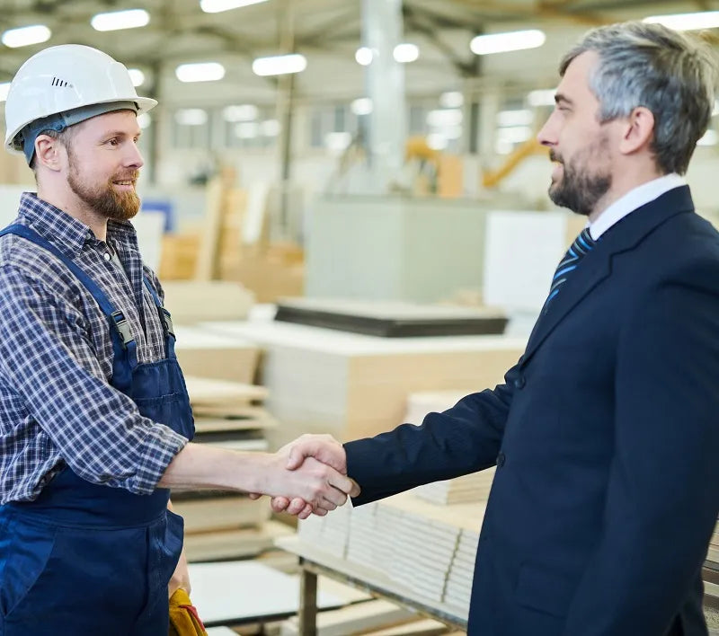 Two men shake hands in plywood factory